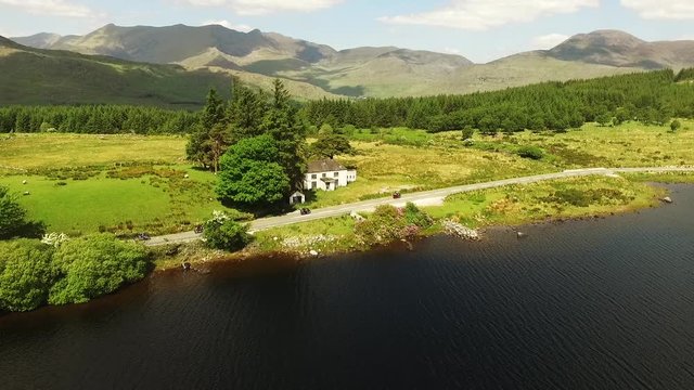 Aerial, motorcyclists drive past lake in Ireland