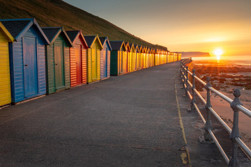 Whitby colourful beach huts on the promenade in North Yorkshire at sunset