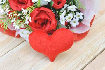 Red roses bouquet and hearts shape put on wooden background. Concept for Valentine's day, Birthday or Wedding. Vintage or light sunshine to the bouquet.