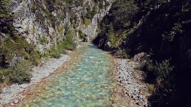 T&uuml;rkisfarbener Bergbach, der durch ein Kiesbett eingerahmt von hohen Felsen flie&szlig;t