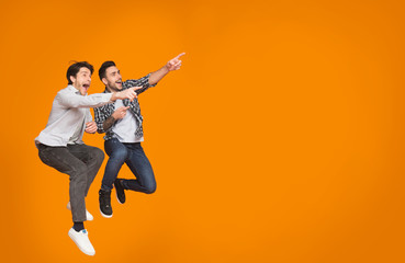 Overjoyed guys pointing at free space and jumping