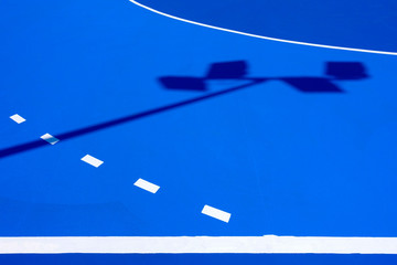 Intense blue background, from the floor of a basketball court to the midday sun, with straight lines and white curves.