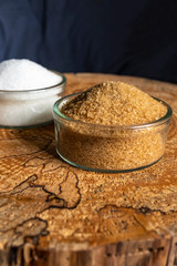 Sweetness, white and brown sugar in glass plates. The question is what to choose. The hopeful background. Vertical photo. Copy space