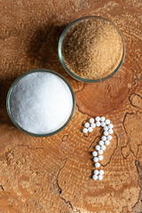 Sugar white and cane or sugar substitute. Question mark what to choose. The hopeful background. View from above.