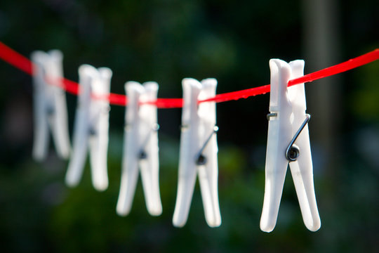 white clothes pegs on a red washing line