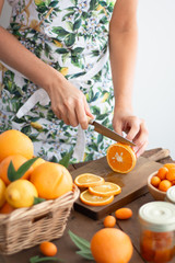 Person with printed kitchen apron cutting an orange in slices