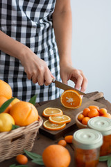 Person with printed kitchen apron cutting an orange in slices