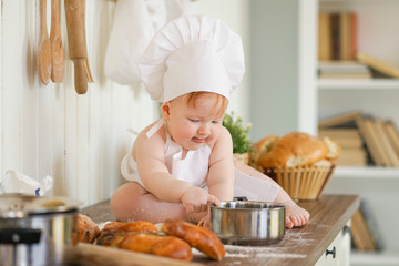 little baker child in chef hat at kitchen table alone