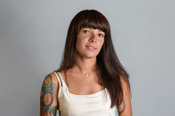 Portrait of a young tanned brunette smiling woman with tattoos