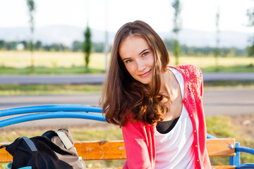 Pretty girl sits on bench in summer park