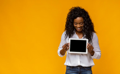 Happy afro girl demonstrating blank digital tablet screen