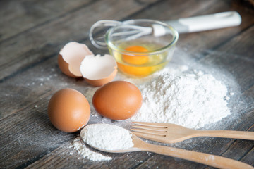 Eggs and flour isolated on wooden table