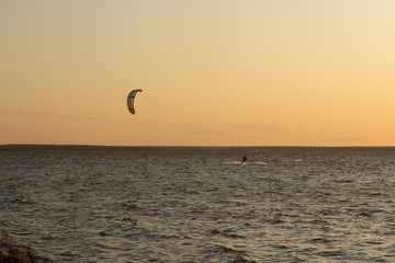 Kite boarding - competition of athletes at sea on a summer evening