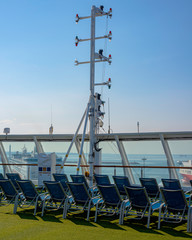 White color satellite antenna of cargo a ship and sun loungers on deck of cruise ship