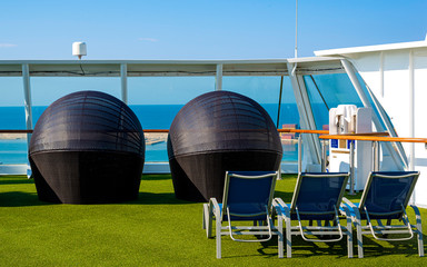 White color satellite antenna of cargo a ship and sun loungers on deck of cruise ship