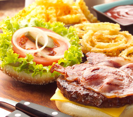 Open Hamburger with Bacon, onion rings and chips on wooden board