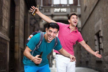Two male fans are drinking beer after football match