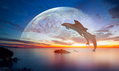 Silhoutte of dolphins jumping up from the sea at sunset with full moon 
