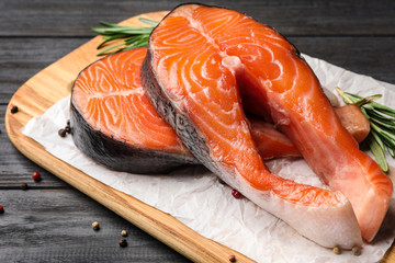Fresh salmon steaks with spices on black wooden table