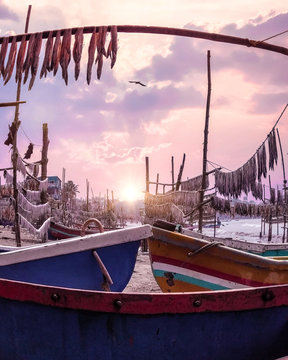 A large sized canoe with various colors on a dock alone.