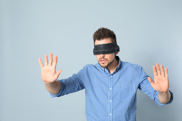 Man with black blindfold on grey background