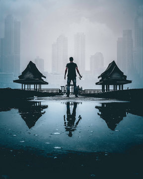 A man standing between little huts with the far off city as a backdrop