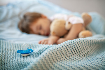Baby boy sleeping with teddy bear and pacifier. Time to sleep concept. Focus on pacifier. Baby needs his sleep! Morning slumber. Cute little kid sleeping. Growing babies need plenty of sleep
