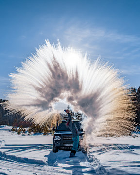 A woman tosses a big whirlwind of snow.