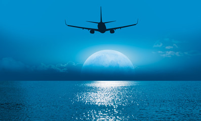 Passenger airplane in the sky against blue full moon "Elements of this image furnished by NASA "