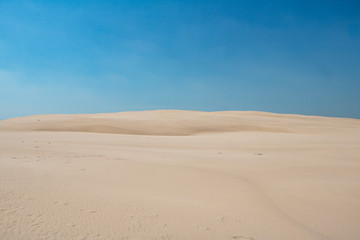 Fototapeta na wymiar White sand dunes on a sunny day with bright blue sky in Slowinski National Park in Leba in Plonad