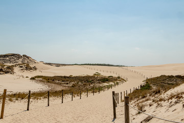 Nature trail in White sand dunes on a sunny day with bright blue sky  in Slowinski National Park in Leba in Plonad