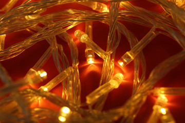 Glowing Christmas lights on red background, closeup
