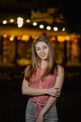 Fototapeta premium Beautiful happy girl in the evening in the park stands with burning lanterns.