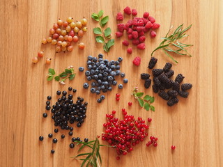 summer berries on a wooden table with greens