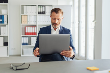 Businessman balancing a laptop on his knee