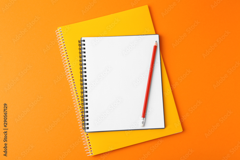 Sticker Notebooks with pencil on orange background, top view