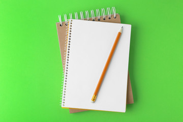 Notebooks with pencil on light green background, top view