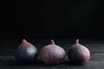 Fototapeta premium Tasty ripe figs on black wooden table against dark background. Space for text