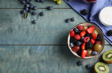 Fresh tasty fruit salad on blue wooden table, flat lay. Space for text