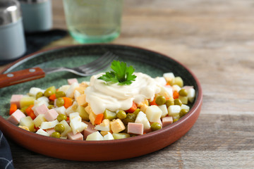 Delicious homemade salad Olivier on wooden table