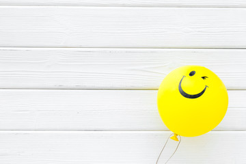 Happiness emotion. Yellow balloon with smile on white wooden background top view space for text