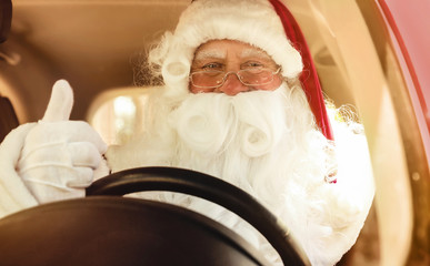 Authentic Santa Claus driving modern car with fir tree, view through windshield