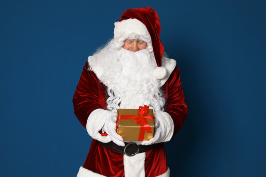 Authentic Santa Claus with gift box on blue background