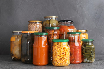 Jars of tasty pickled vegetables on grey table