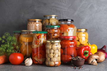Jars of tasty pickled vegetables on grey table