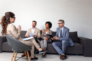 Group of four people at office meeting sitting on sofa