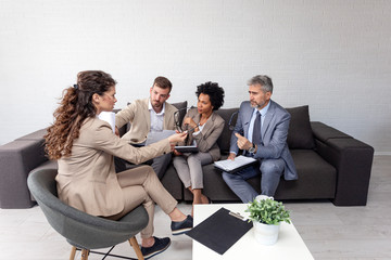 Group of four people at office meeting sitting on sofa