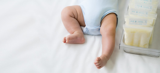Leg of newborn baby and breast milk frozen in storage plastic bag, Breastfeeding from pumping milk...