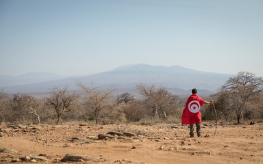 man, wearing a tunisian flag over his shoulders, in a nature, looking at a landscape