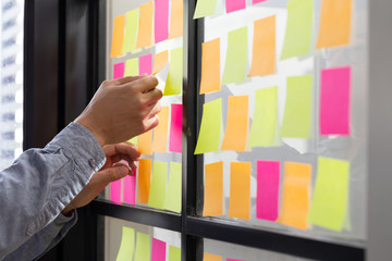 IT worker tracking his tasks on kanban board. Using task control of agile development methodology. Man attaching sticky note to scrum task board in the office - obrazy, fototapety, plakaty